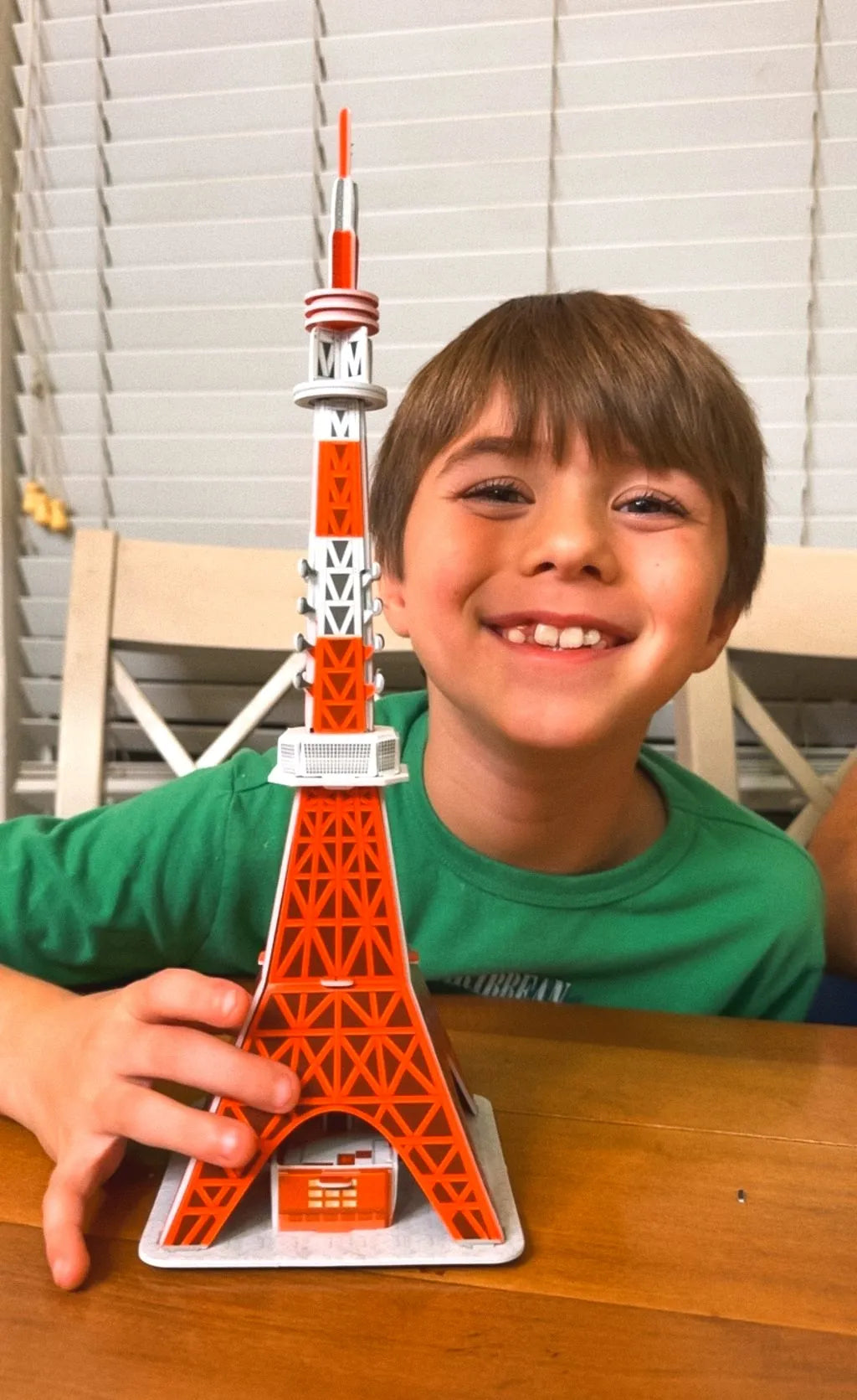 A smiling boy holding the Tokyo Tower model he built